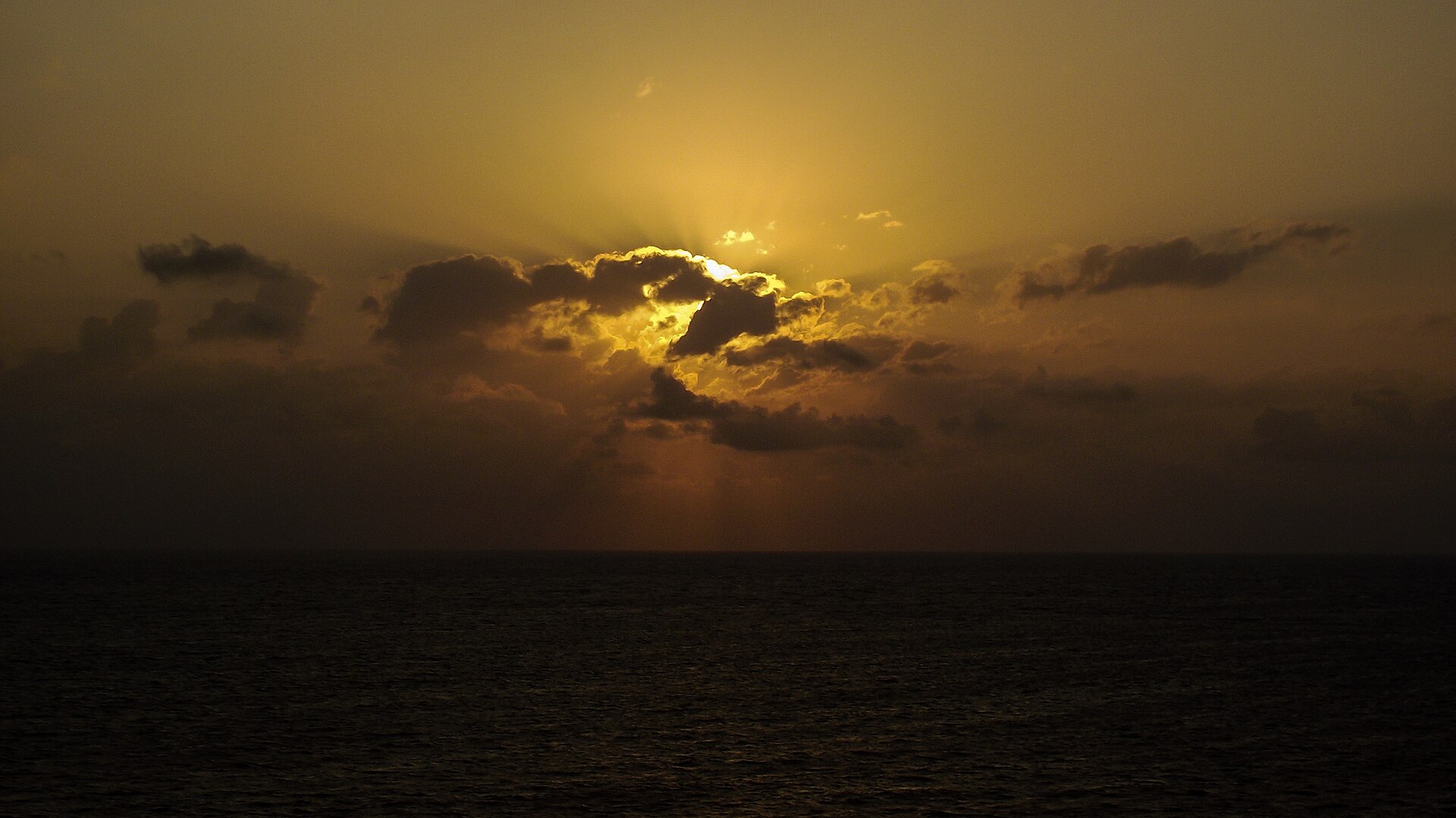 The sun rising through clouds over the sea, seen from Ponta do Seixas
