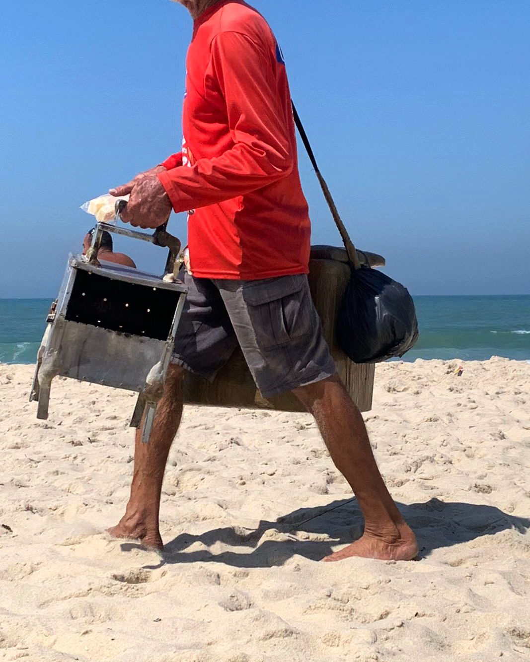 A curd cheese seller crossing the sand with his portable grill